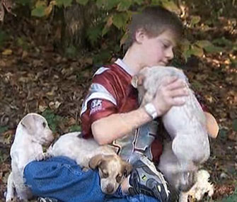 Kyle Camp plays with the puppies who kept him warm while he was lost in the woods.
