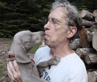 William Wegman gets a kiss from one of his dogs.