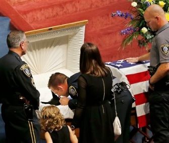 Oklahoma City police officer Sgt. Ryan Stark, center, leans over the casket of his canine partner, Kye