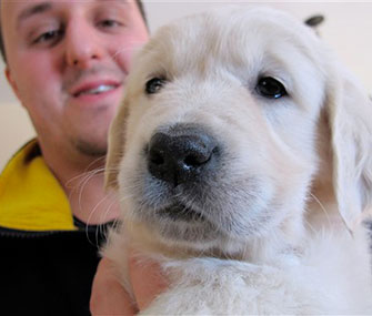 Trainer Jake Guell holds a Golden Retriever puppy who he'll train to become a therapy dog for teenager Teagan Marti.