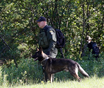 A law enforcement officer and dog search for escaped prisoners Richard Matt and David Sweat in New York last week.