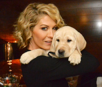Jenna Elfman of the NBC series "Growing up Fisher" holds a puppy who will trained to be a guide dog