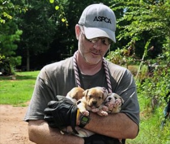 An official carries puppies who were rescued from a home in Alabama.