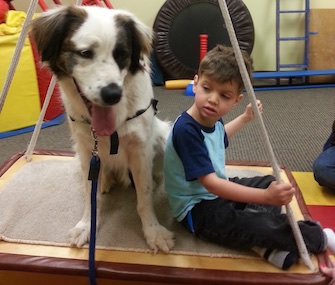 Juan, a 3-year-old mixed breed rescue dog, keeps Jayden company on a swing. The swing helps Jayden with balance, core strength and focus, among other things.