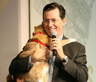 Comedian Stephen Colbert gets a hug from a cat at a book signing event.